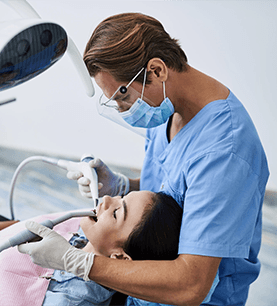 Side view portrait of stomatologist in sterile gloves doing dental procedure while patient with closed eyes sitting in dentist chair